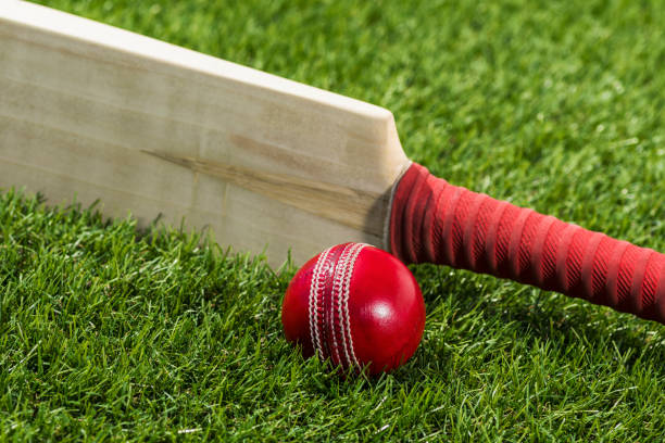 istock Looking down on a Cricket ball sitting in the grass with a bat on edge 947363958