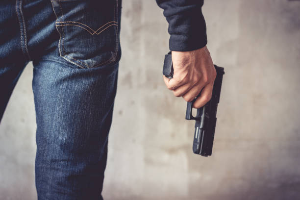 cerca del hombre que sostiene el arma de la mano. hombre vestido con pantalones vaqueros azules. concepto de terrorista y ladrón. concepto de policía y soldado. tema de armas - armamento fotografías e imágenes de stock