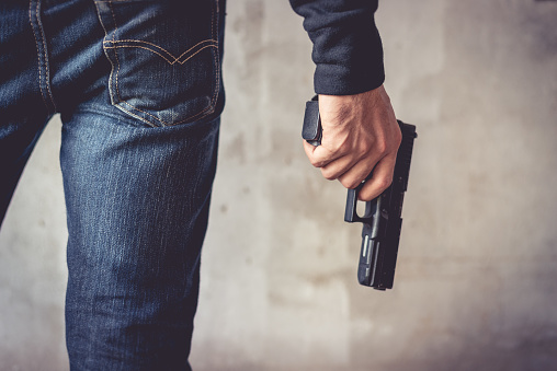 Close up of man holding hand gun. Man wearing blue jeans. Terrorist and Robber concept. Police and Soldier concept. Weapon theme