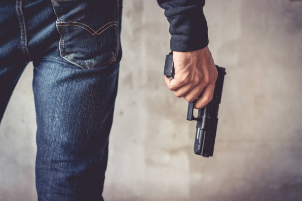 Close up of man holding hand gun. Man wearing blue jeans. Terrorist and Robber concept. Police and Soldier concept. Weapon theme stock photo