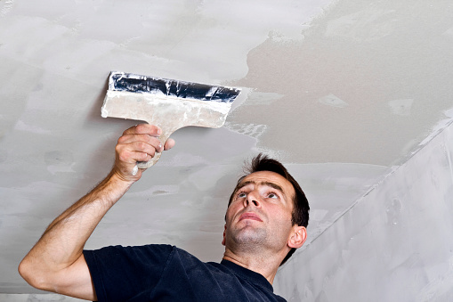 A young woman installing a ceiling light for  DIY kitchen remodel.