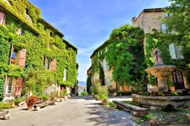Leafy town square with fountain in the beautiful village of Saignon, Provence, France