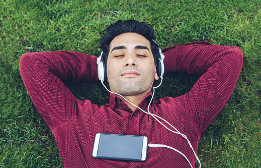 Young man relaxing in the park and listening music