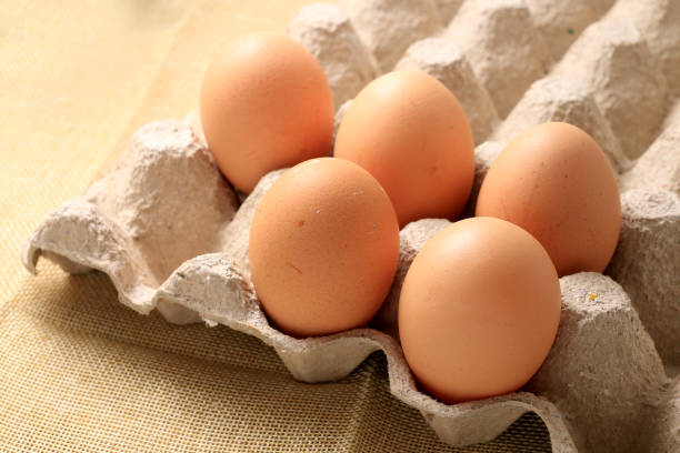 istock Fresh chicken eggs In the thirty box paper and have empty space for egg on cream fabric background. 947382196