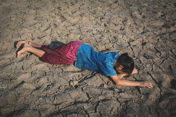 istock High Angle View Of Girl Lying On Field During Drought 947387486