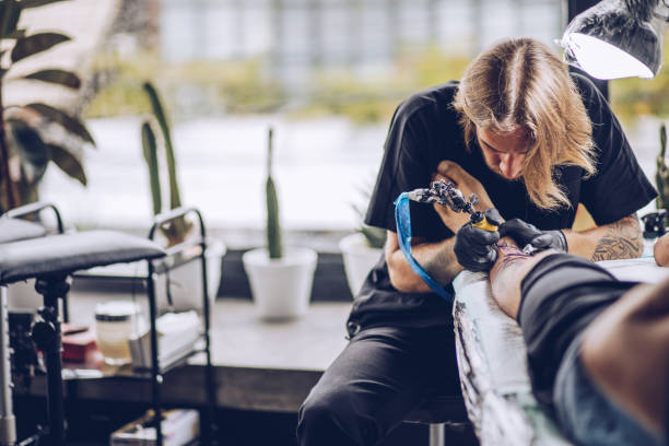 istock Guy getting a new leg tattoo 947393180