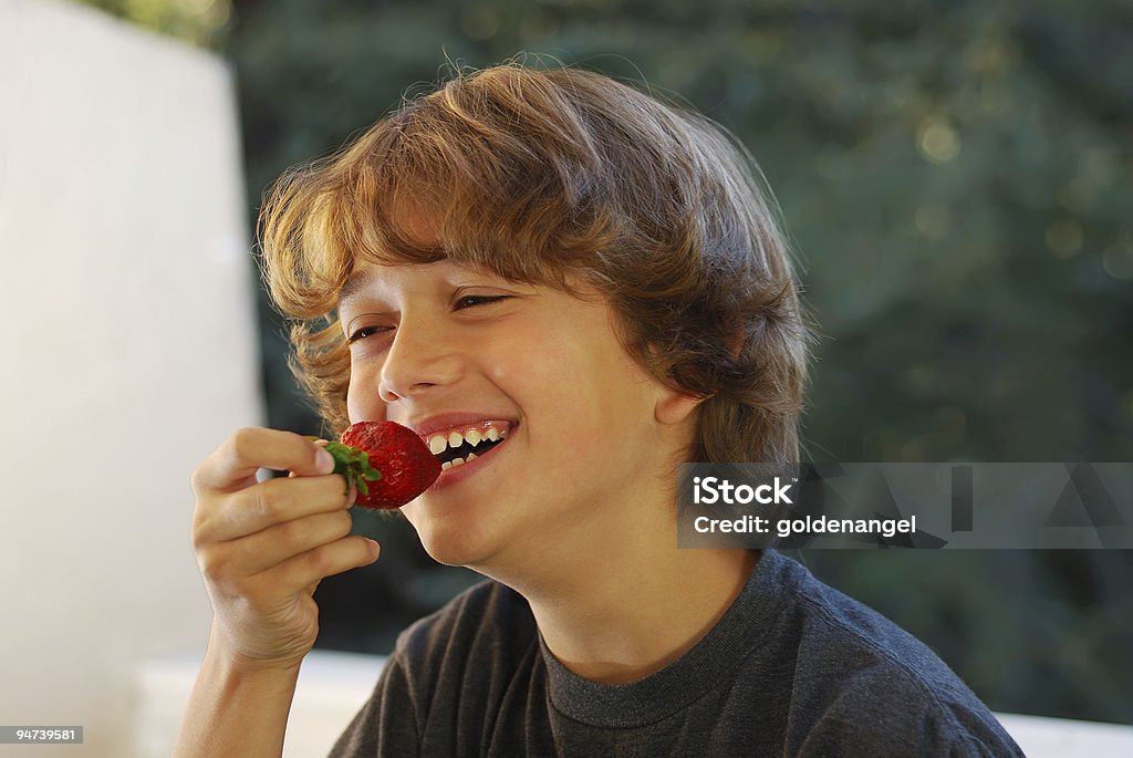 Подростковой мальчик ест клубнику - Стоковые фото Клубника роялти-фри