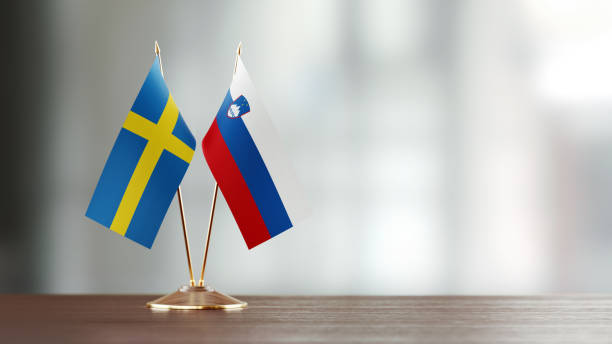 istock Swedish And Slovenian Flag Pair On A Desk Over Defocused Background 947396772