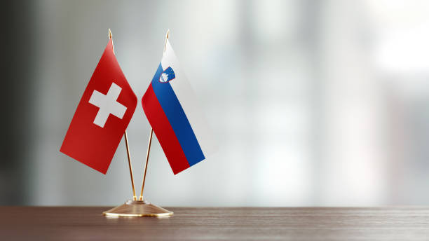 istock Swiss And Slovenian Flag Pair On A Desk Over Defocused Background 947397680