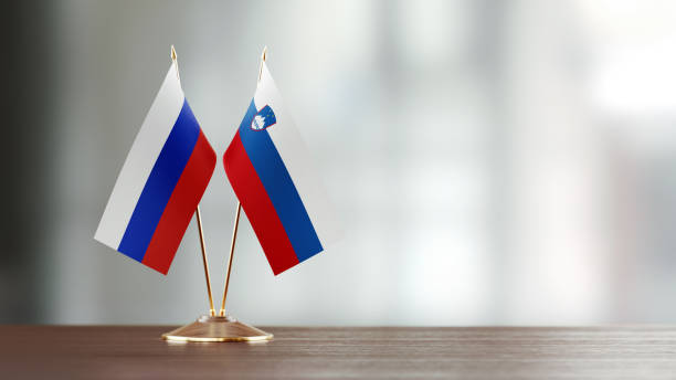 istock Russian And Slovenian Flag Pair On A Desk Over Defocused Background 947401298