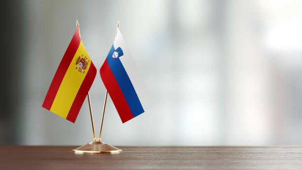 istock Spanish And Slovenian Flag Pair On A Desk Over Defocused Background 947401662