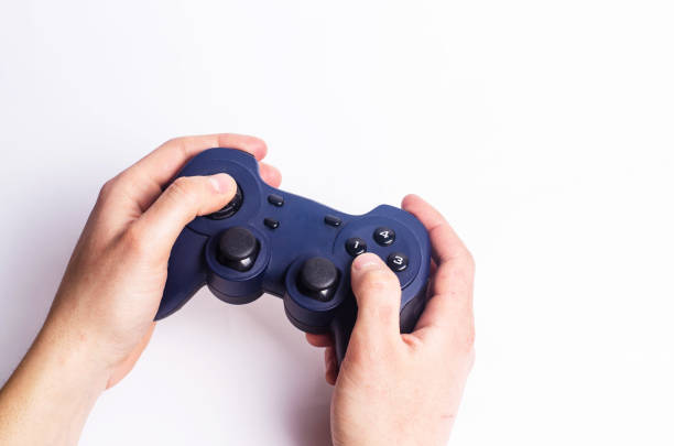 A young guy holds a joystick and plays computer games on a white background. Blue joystick in the hands of man. The concept of computer games and entertainment at home. Game addiction, eSports.