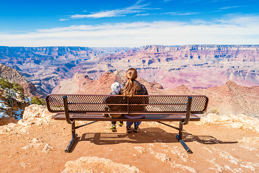 Stock photograph of a mother with child looking at view in Grand Canyon National Park, South Rim, USA on a sunny day.