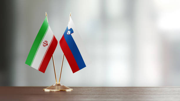 istock Iranian And Slovenian Flag Pair On A Desk Over Defocused Background 947414666