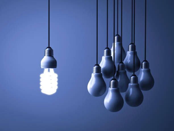 istock One hanging eco energy saving light bulb glowing and standing out isolated from unlit incandescent bulbs on dark blue background , leadership and different creative idea concept 947418022