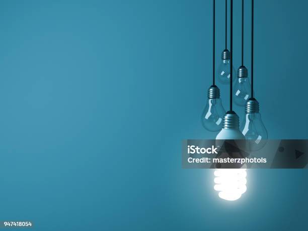 One Hanging Eco Energy Saving Light Bulb Glowing And Standing Out From Unlit Incandescent Bulbs On Dark Green Pastel Color Background Leadership And Different Creative Idea Concept 3d Rendering Stock Photo - Download Image Now