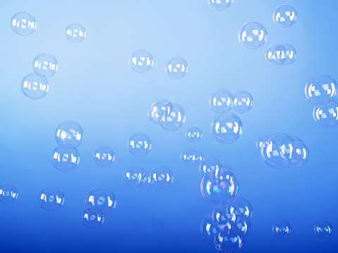 Multiple bubbles caught floating in air against blue background