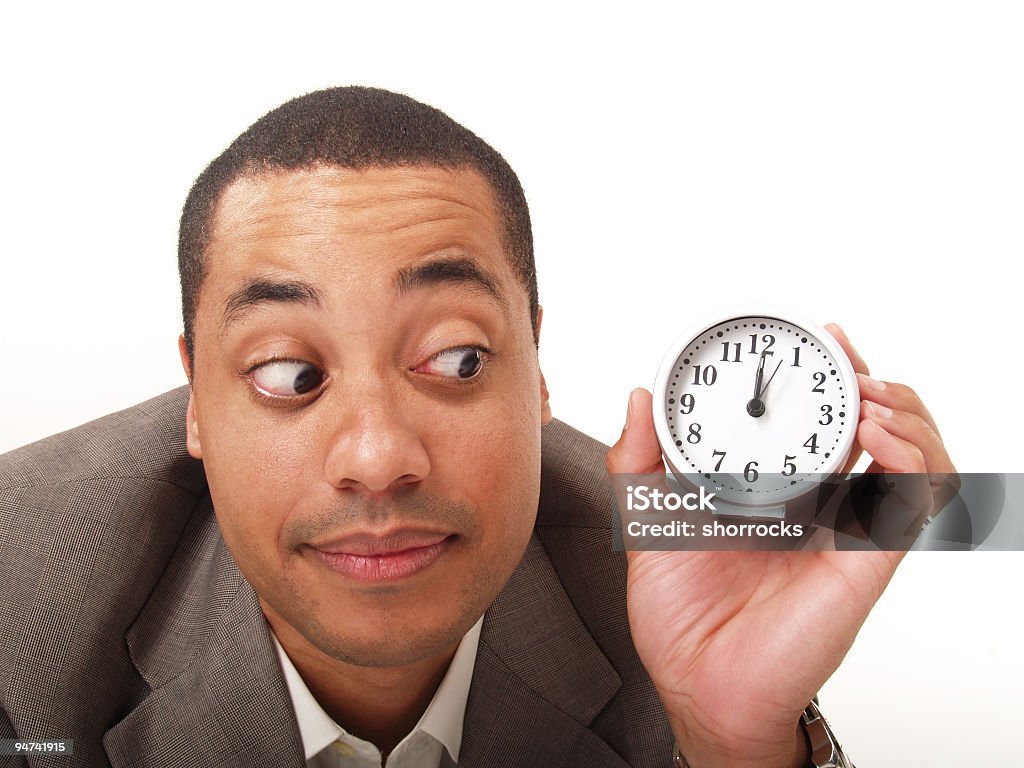 It's About Time! Head shot of attractive business man looking with concern at a clock he's holding in his hand; watching the time; copy space Checking the Time Stock Photo