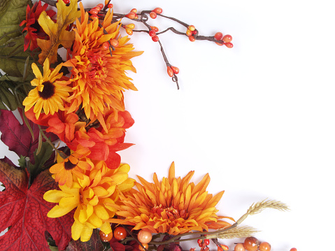 Colorful autumn frame of silk flowers and leaves with soft shadow; copy space 