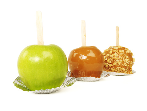 Close up of three apples (Granny Smith, caramel, caramel with chopped peanuts) in a diagonal line on white; a simple autumn treat