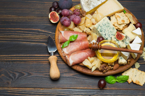 istock Camembert cheese and prosciutto with honey, figs, walnuts on wooden board 947434740