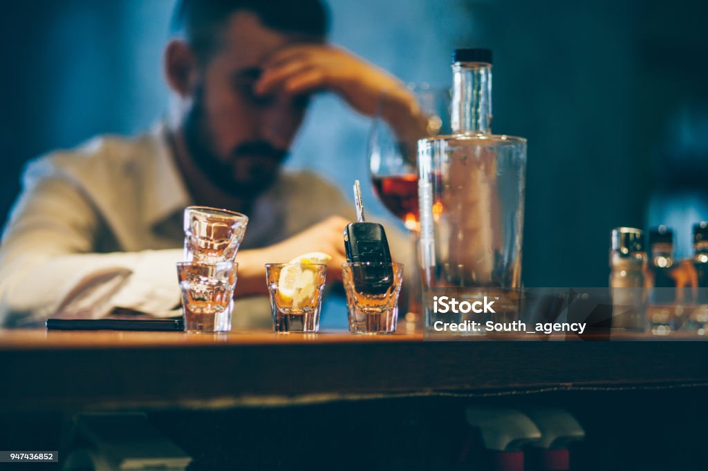Drinking alone One man, sitting at the bar counter alone, he has drinking problems. Alcohol Abuse Stock Photo