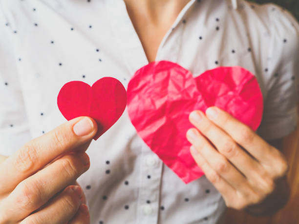 istock Donated heart. Large and small red heart in his hand. 947437046