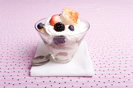 Berries layered with fresh whipped cream and shortcake in a fancy glass; copy space 