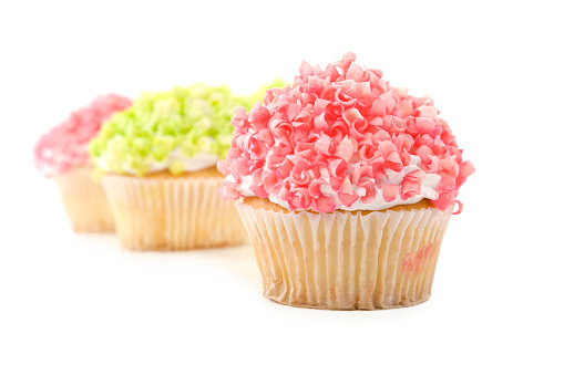 Cupcakes with pink and green shavings on top on white background; soft shadow and copy space 