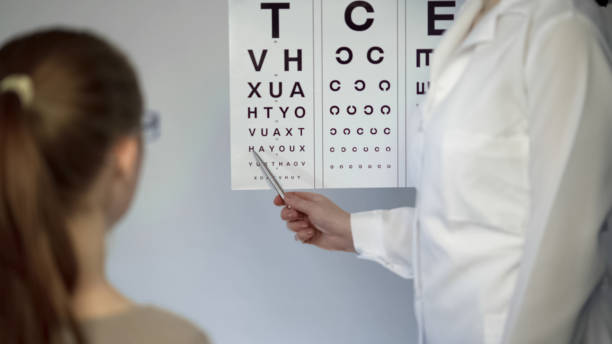 school girl in glasses reading during medical checkup, eyesight examination - medical exam doctor patient adult imagens e fotografias de stock