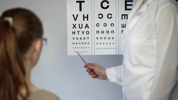 istock Eye doctor pointing at table with small letters, checking patients eyesight 947450758