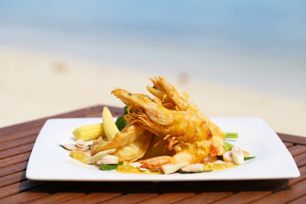 istock Fried Shrimp on decoration vegetable on wooden table with beach view 947464718