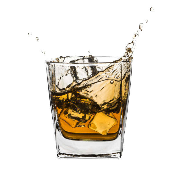 istock Glass of splashing whiskey isolated on white 947467492