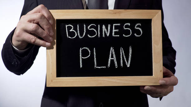istock Business plan written on blackboard, male hands holding sign, strategy, goals 947471334