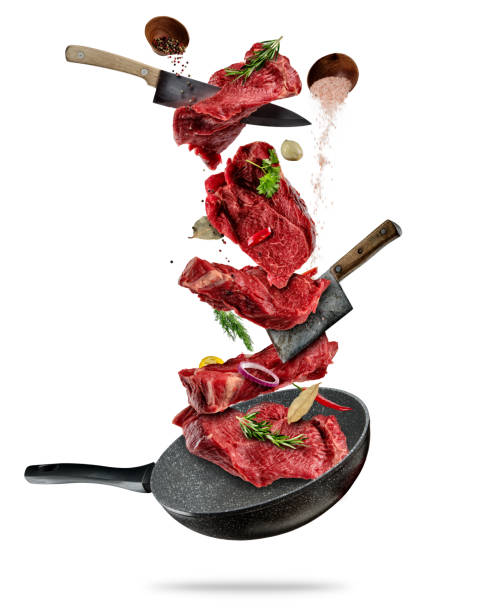 istock Flying pieces of beef steaks from pan on white background 947472136