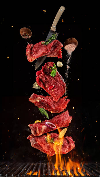 Flying pieces of raw beef steaks from grill grid on black background. Flying pieces of raw beef steaks from grill grid, isolated on black background. Concept of flying food, very high resolution image steak vertical beef meat stock pictures, royalty-free photos & images
