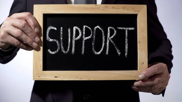 istock Support written on blackboard, businessman holding sign, business concept 947472582