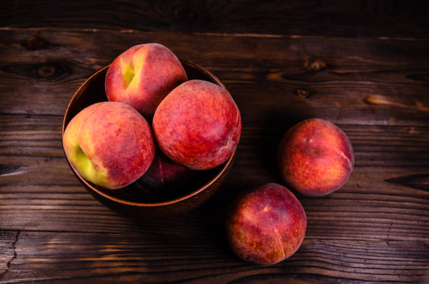 istock Peaches in a bowl on wooden table 947472876