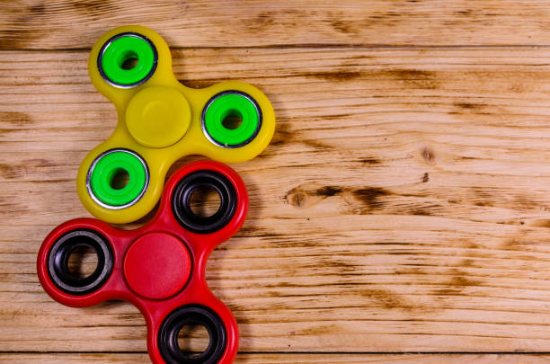 istock Two fidget spinners on wooden desk. Top view 947472912