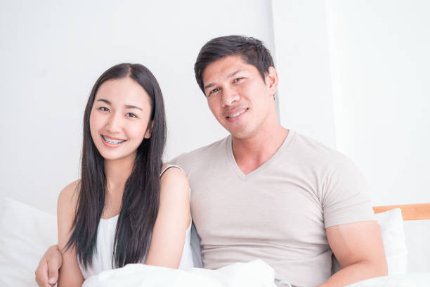 istock Happy Asian couple on bed with bright morning light 947479168