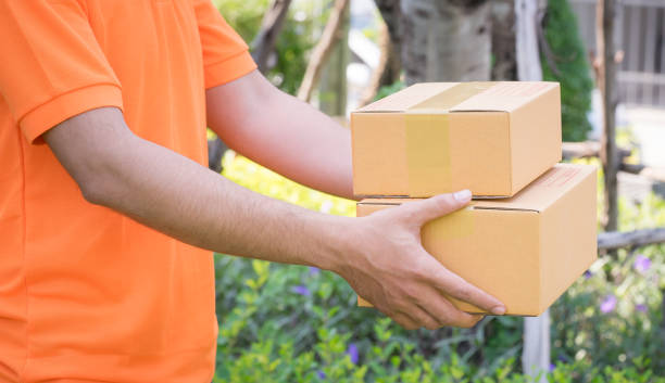 istock Delivery man in orange is handing packages 947479460