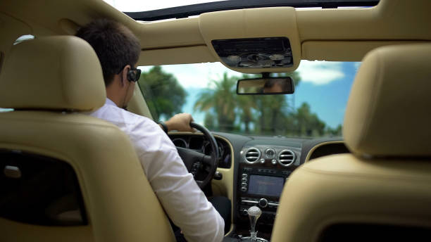 istock Businessman driving car and talking on phone over wireless headset, technology 947479666