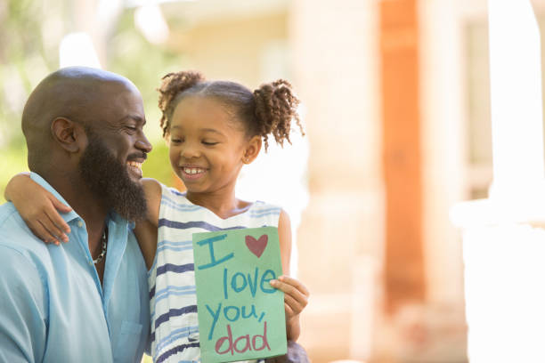Happy Father's Day. Girl gives card to dad. Happy Father's Day.  Little girl gives homemade card to her dad in front yard of family home.  African descent family. i love you photos stock pictures, royalty-free photos & images