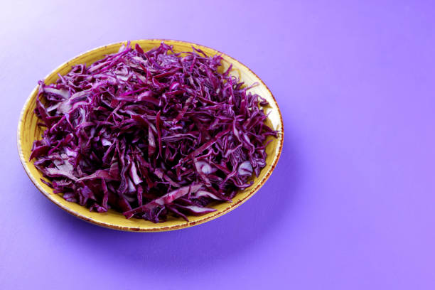 istock Chopped cabbage on a violet background, red cabbage on a yellow plate, copy space, top view, vegetarian food, fresh vegetables for salad, ultraviolet background, minimalism 947491774