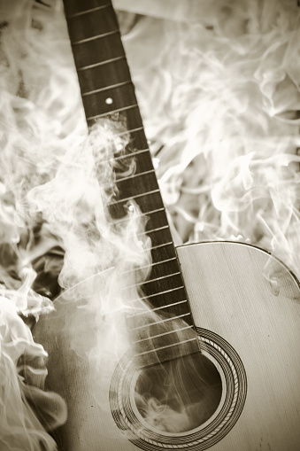 A stringless acoustic guitar is burning in a raging fire.