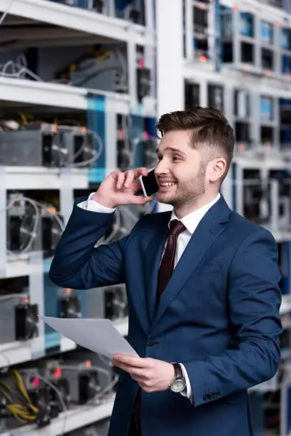 happy young businessman talking by phone at ethereum mining farm