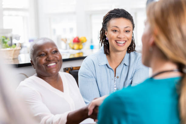 cheerful senior woman greets home healthcare nurse - doctor patient greeting talking imagens e fotografias de stock