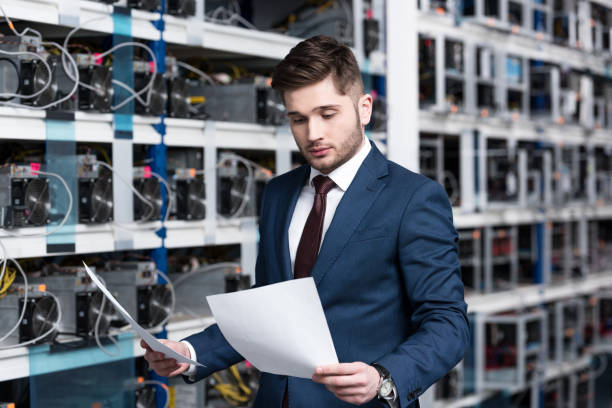 istock handsome young businessman reading business documents at cryptocurrency mining farm 947506770
