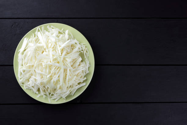 istock Chopped cabbage on a black background, white cabbage on a green plate, copy space, top view, vegetarian food, fresh vegetables on dark boards, black background, minimalism 947514630