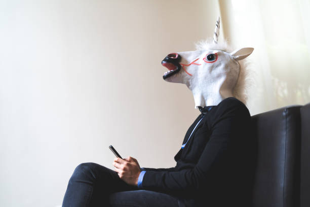 istock Business man with Unicorn Mask Using Mobile at Office 947516318
